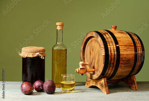 Friesh plum brandy and a wooden barrel on a table photo