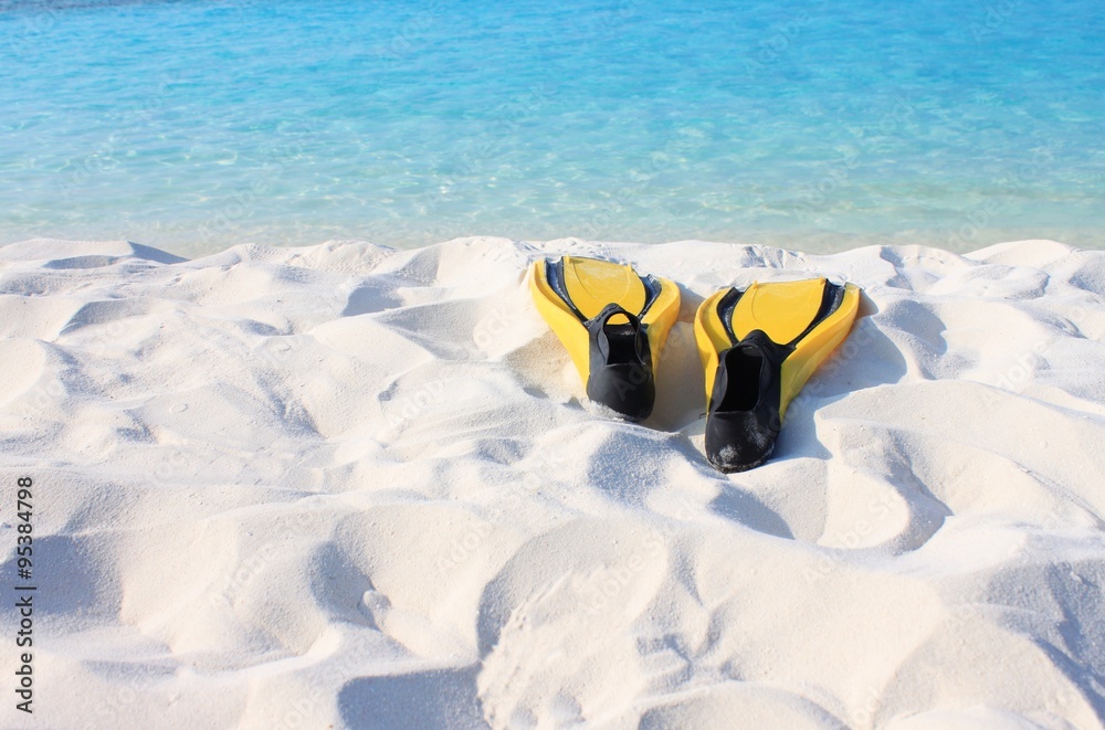 Obraz premium Bright fins on beach prepared for snorkeling, turquoise sea and white sand coast. Tropical island. Empty vacation at seaside background.