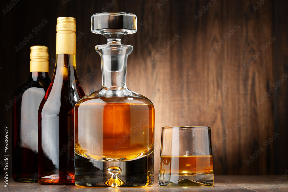 Bottles of assorted alcoholic beverages and glass of whisky Bottles of assorted alcoholic beverages and glass of whisky