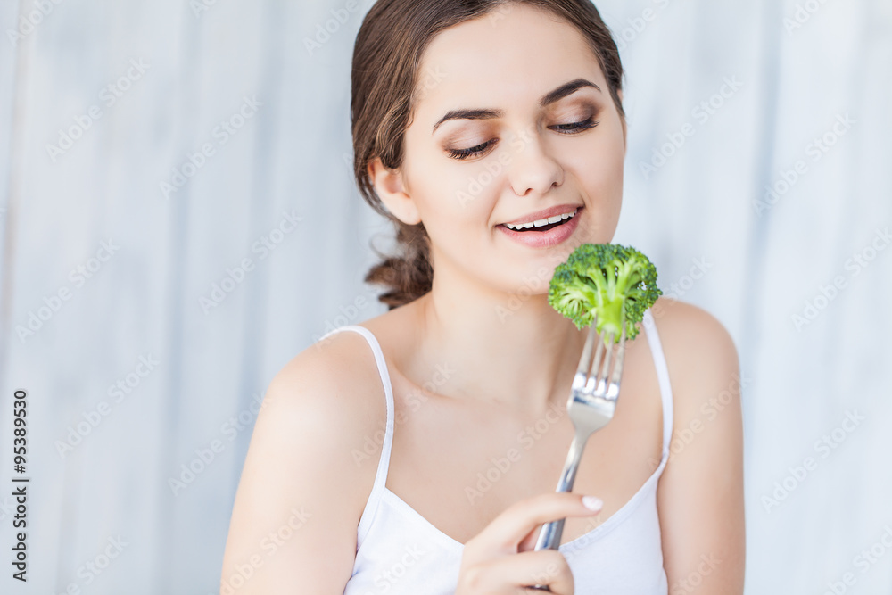 Portrait of happy smiling young beautiful woman eating broccoli Portrait of happy smiling young beautiful woman eating broccoli