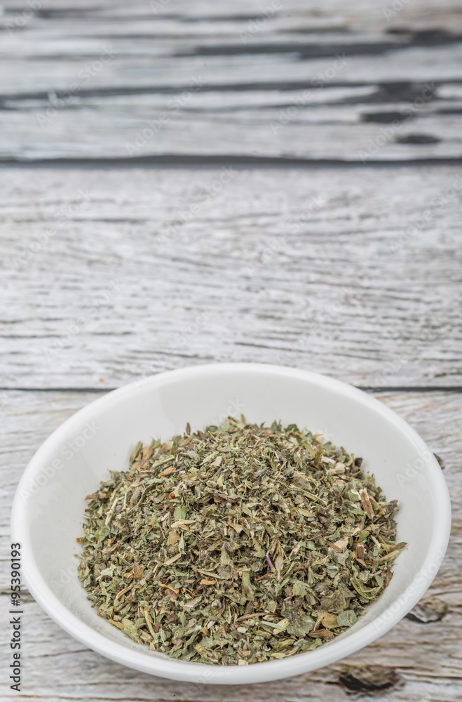Dried lemon balm leaves in white bowl over wooden background Dried lemon balm leaves in white bowl over wooden background