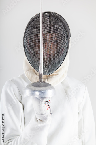 Portrait of woman wearing white fencing costume practicing with the sword