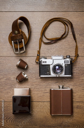 Vintage camera and leather belt on wooden floor