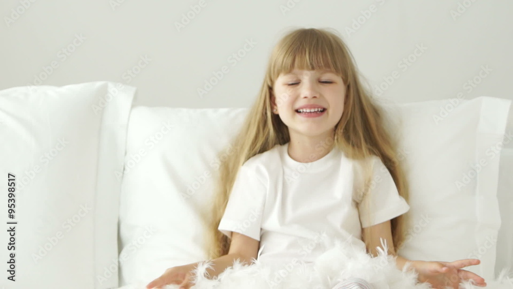 Funny little girl playing with pillow feathers and laughing Funny little girl playing with pillow feathers and laughing