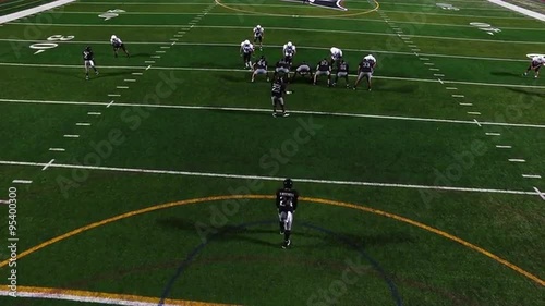 A football player punts the ball during a game, view from above
