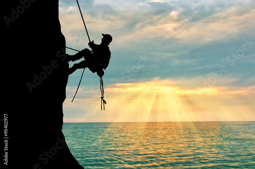 Silhouette climber climbing a mountain photo