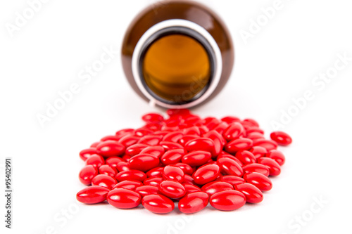 Bunch of red pills felt out from container on table photo