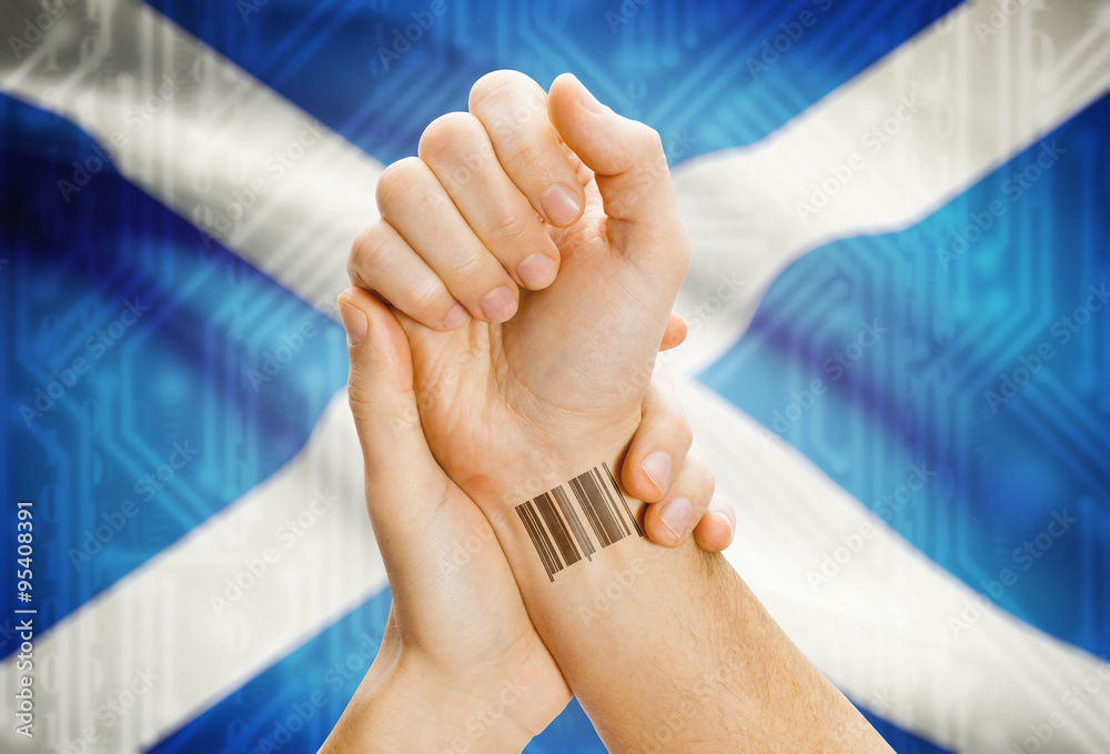 Barcode ID number on wrist and national flag on background - Scotland