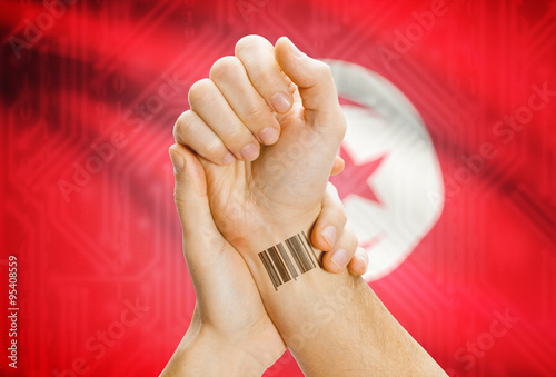 Barcode ID number on wrist and national flag on background - Tunisia
