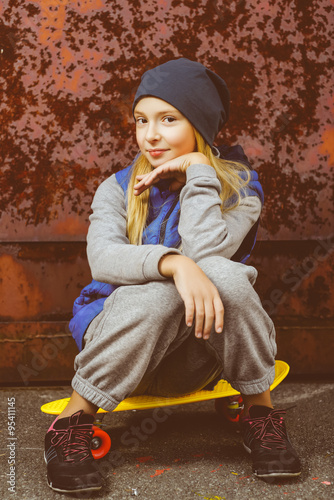 Smiling girl holding color plastic penny board or skateboards outdoor and showing Ok