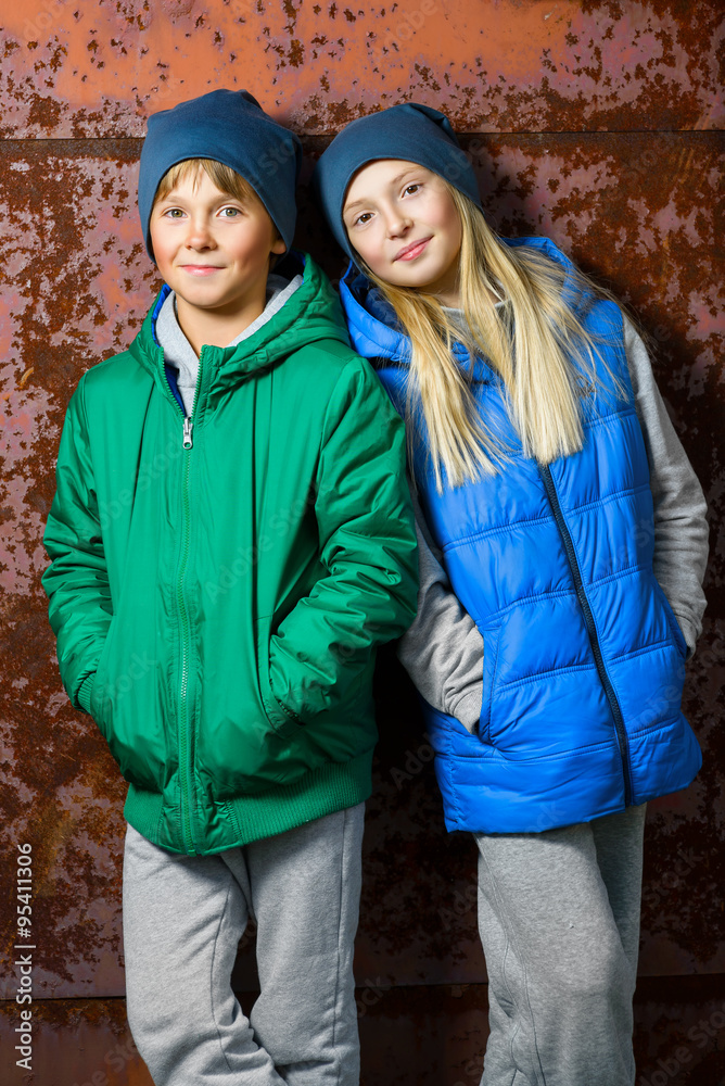 Hipster girl and boy standing against red rusty wall Hipster girl and boy standing against red rusty wall