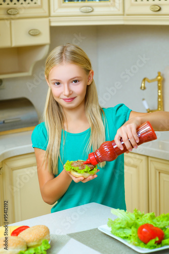 smiling girl make homemade hamburger or sandwiche at kitchen