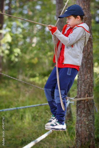 Cute little boy having fun outdoors climbing on playground © levranii