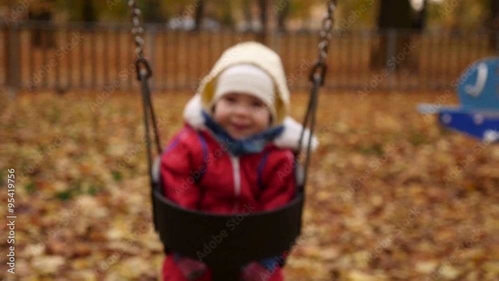Happy baby on swing in autumn park front view slow motion Happy baby on swing in autumn park front view slow motion