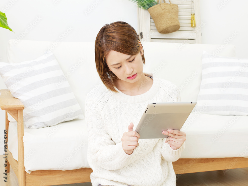 部屋でタブレット使う女性 落ち込む 部屋でタブレット使う女性 落ち込む