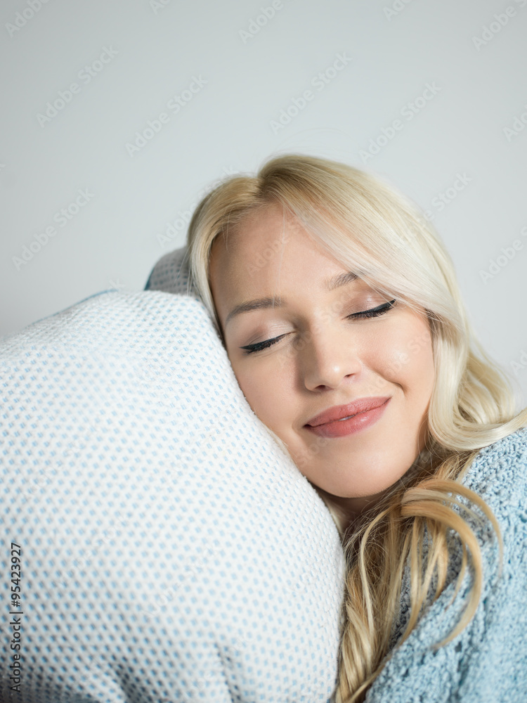 close up of a charming woman with pillow sitting on her bed look close up of a charming woman with pillow sitting on her bed look