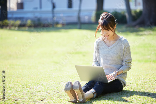 芝生の上でパソコンを使う女性