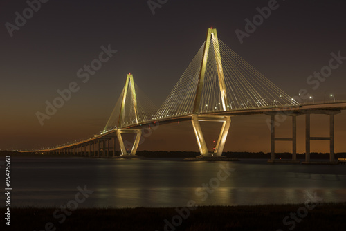 Arthur Ravenel Jr. Bridge illuminated aginst a darkening dusk sky. The bridge carries eight lanes of traffic over the Cooper River between Charleston and Mount Pleasant, SC. 