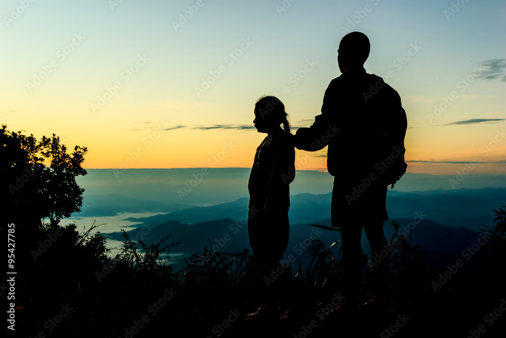 Two children, male and female standing against the sun, sunrise,