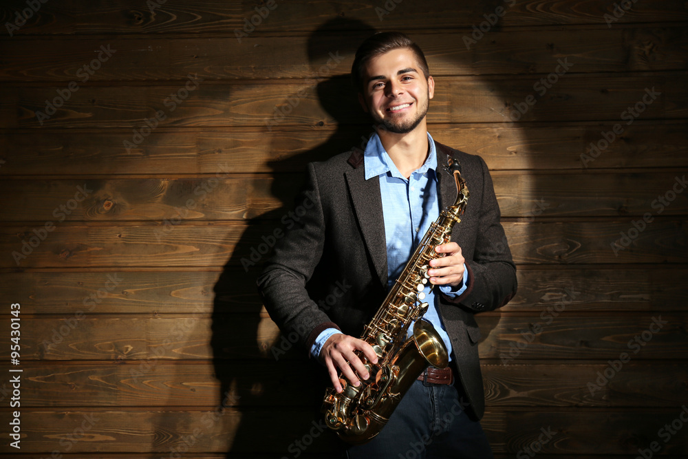 Naklejka premium Elegant saxophonist plays jazz on wooden background
