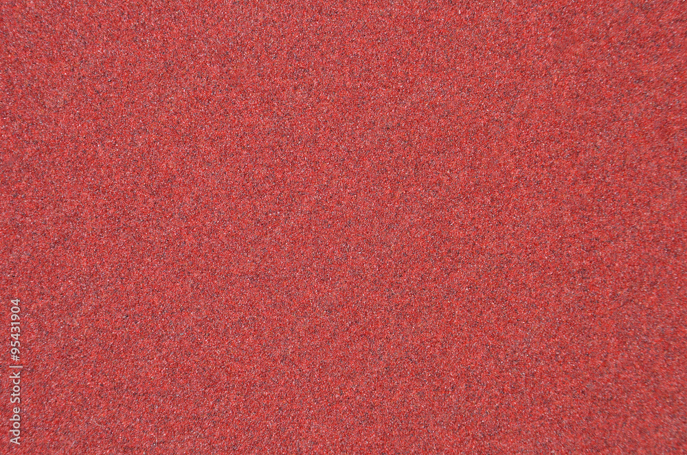 Fototapeta premium Red rough textured sandpaper background, close up