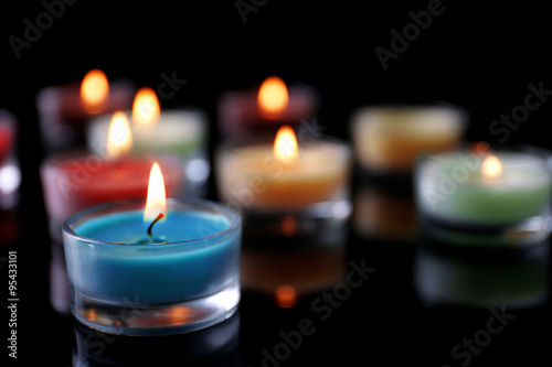 Colourful alight candles in a row on black background  blurred