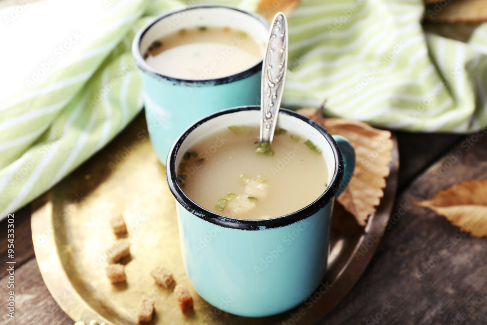 Two mugs of soup on a metal tray Two mugs of soup on a metal tray