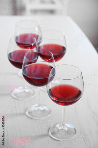 Glasses of red wine on table on bright background