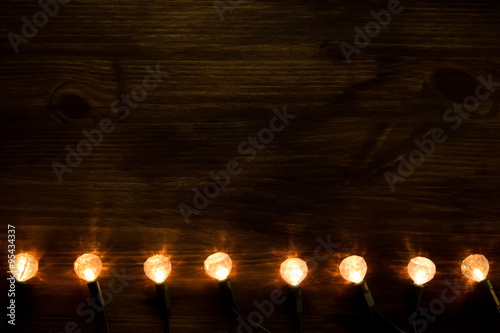 yellow Christmas lights on wooden background. Christmas background