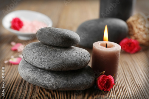 Relax set which include aroma candles  flowers  petals and pebbles on wooden background