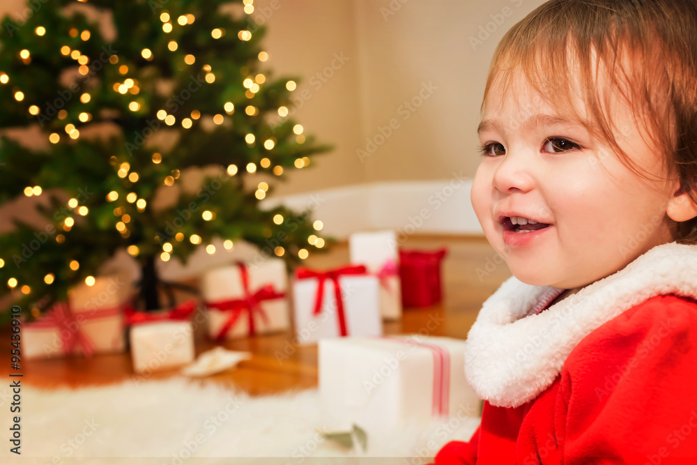 Toddler girl smiling in front of the Christmas tree Toddler girl smiling in front of the Christmas tree