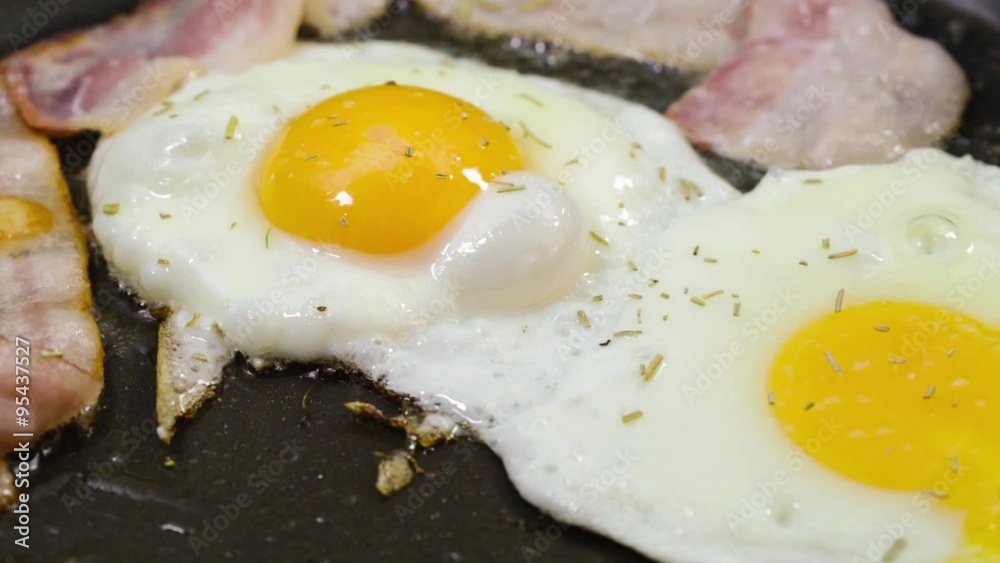 Eggs and Bacon. Three strips of bacon frying in a pan with an egg. Eggs and Bacon. Three strips of bacon frying in a pan with an egg.