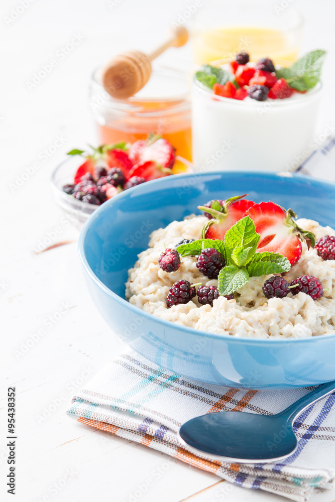 Breakfast - oatmeal with honey and berries, blue bowl Breakfast - oatmeal with honey and berries, blue bowl