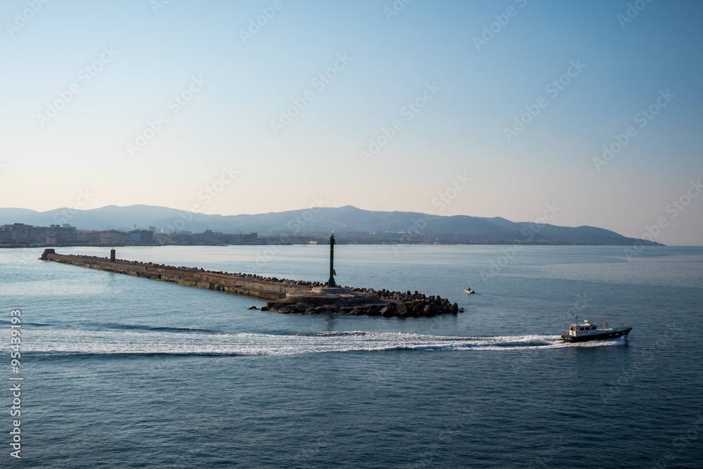 Breakwater with gates to harbor in it at sunrise with cloudless sky