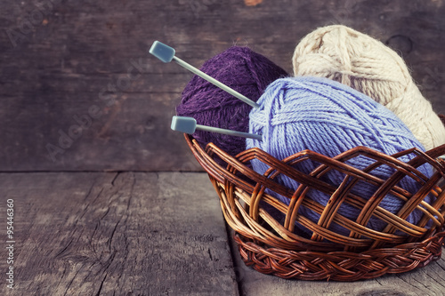 Skeins colored yarn and knitting needles in a basket