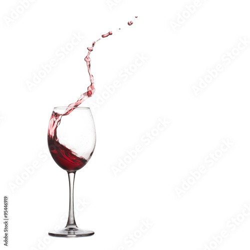 Wine glass splash and drops. Pouring red dry, splashing into crystal glass, close-up, white background. copy space