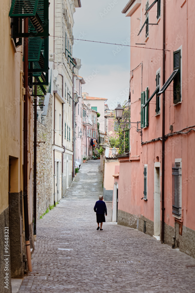 A old woman walking alone in a narrow street