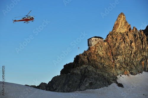 helicopter at dawn supplying swiss mountain refuge. Bertol cabin. photo