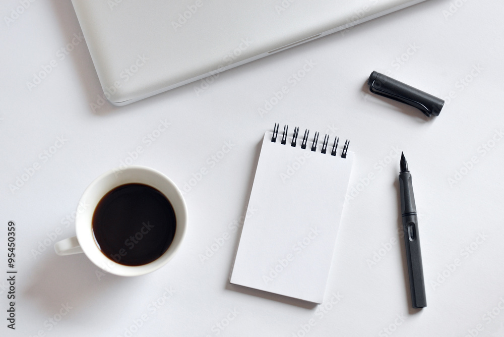 Coffee cup, spiral notebook, laptop, and pen on white background Coffee cup, spiral notebook, laptop, and pen on white background
