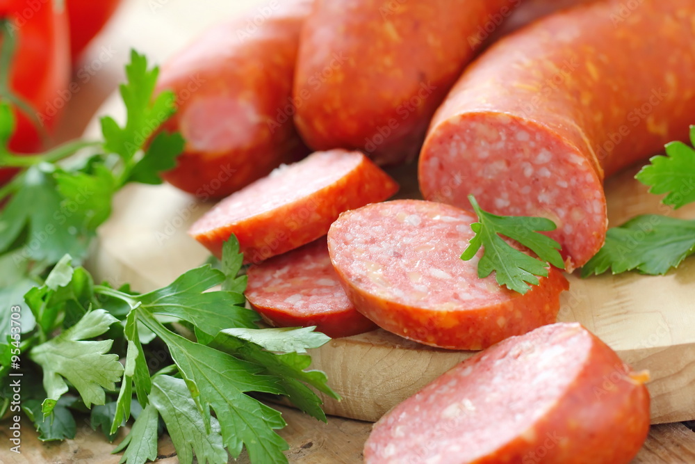 Smoked sausage with spices and vegetables on wooden table Smoked sausage with spices and vegetables on wooden table