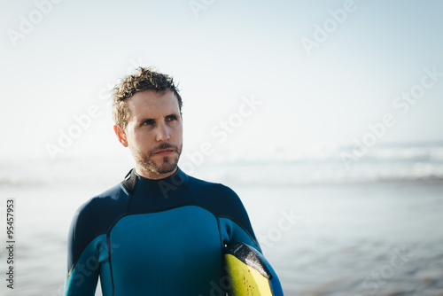 Male surfer beach lifestyle portrait. Man in wetsuit with bodyboard surfing equipment. photo