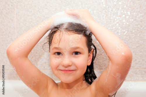 Happy little kid is washing hair