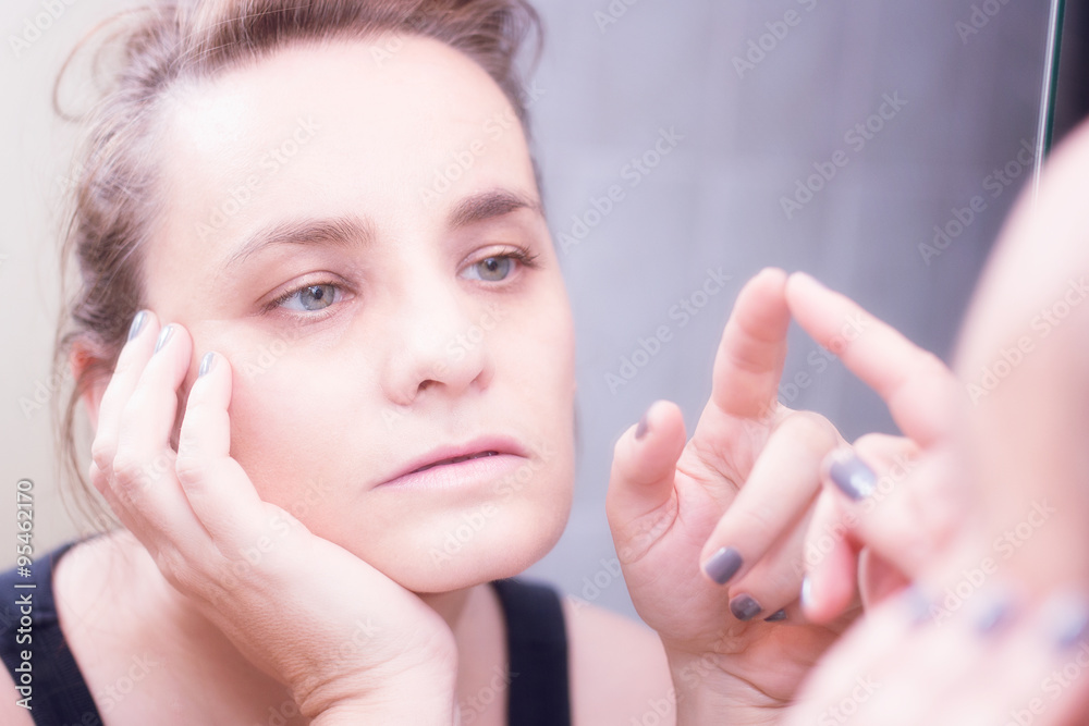 Fototapeta premium Bored woman looking at her own reflection, sad and lonely
