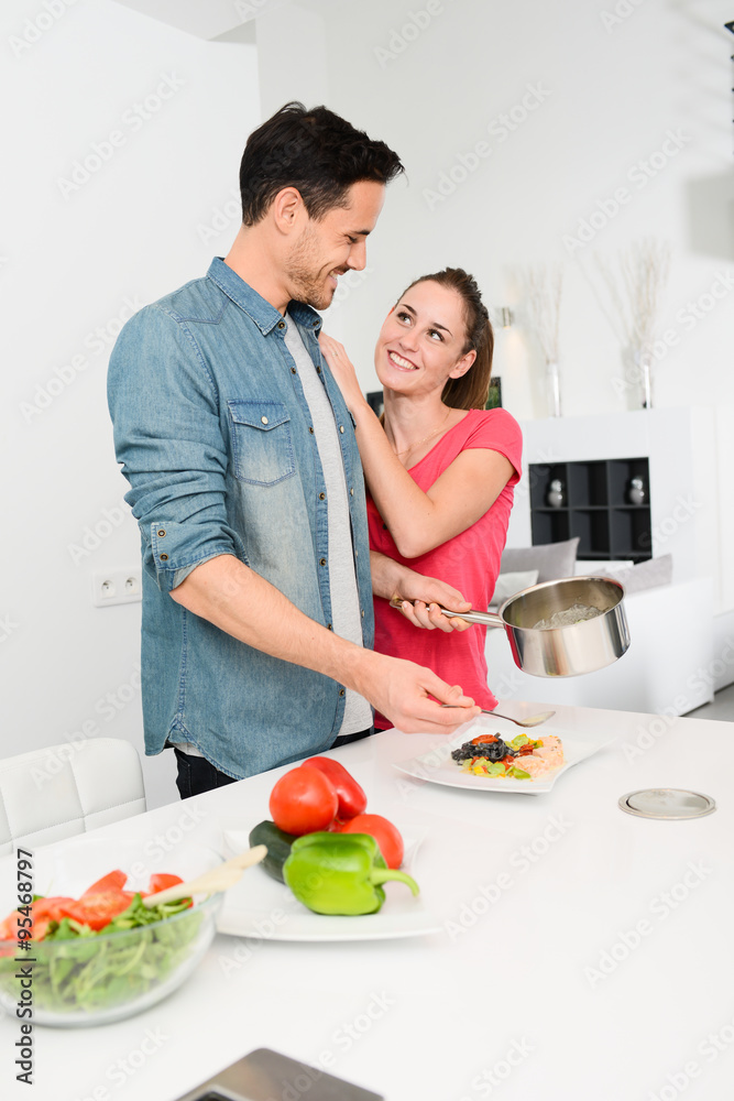 beautiful and happy young couple having fun cooking together fresh food in kitchen at home