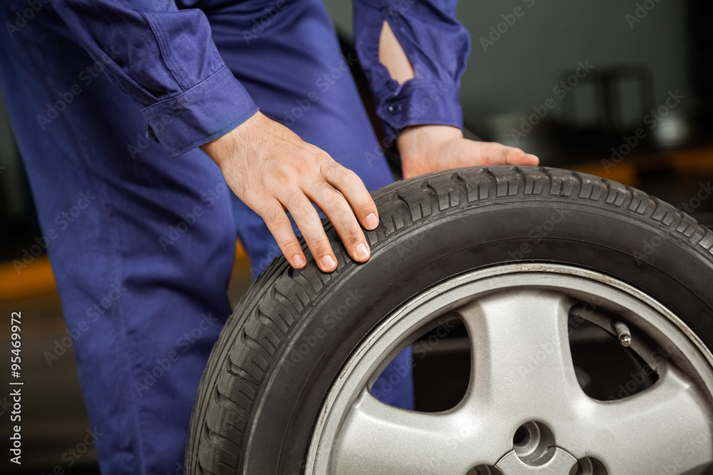 Fototapeta premium Mechanic Holding Tire At Garage
