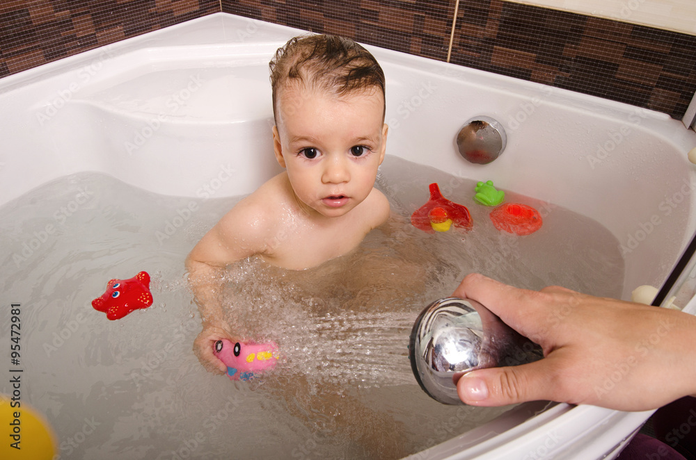 Toddler taking a bath. Little baby in a bathtub, mother's hand washing