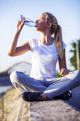 Cute blonde girl drinking water on training, outside