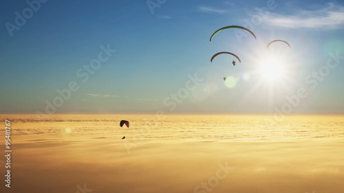 Paragliders on a sea of golden clouds with sun