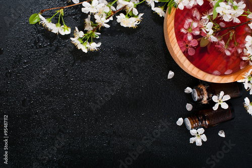 Spa concept on a dark background. Sea salt, flowering branches of cherry, aromatic oils photo