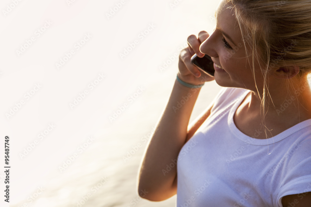 Blonde young girl talking on the phone, close to the sea Blonde young girl talking on the phone, close to the sea